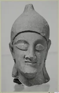 Neo-Cypriote limestone head from Kition with a tall pointed headdress and lowered eyes
