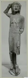 Limestone statue from Kition of a standing figure with one hand raised to the head and the other at the chest.