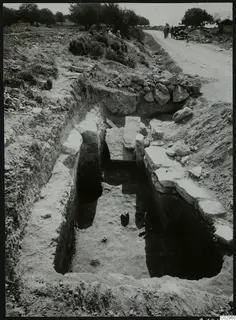 Tomb 13 at Amathus: an excavated sloping passage with cut stone blocks, a dirt road and a car beside it