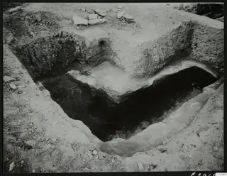 Excavated cutting at Amathus with pale stone blocks and slabs exposed in the trench floor.