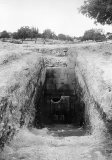 Dromos of Tomb 2 at Amathus before opening, with a squared stone wall and an upright slab at the far end.