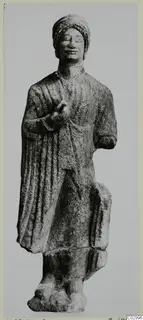 Limestone standing figure from Vouni with a wrapped headdress and right hand raised to the chest.