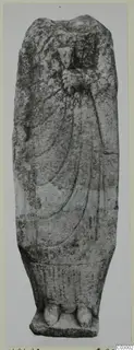 Limestone statue from Vouni of a standing draped figure with a broken head, one hand raised to the chest.