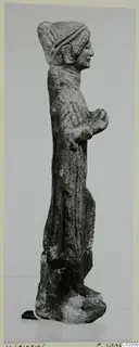 Limestone standing figure from Vouni, seen in profile, with a headdress and long garment