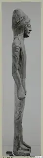 Limestone statue of a standing figure from Vouni, shown in side profile with a tall headdress and arms at its sides