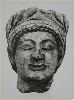 Carved limestone head of a woman from Vouni with closed eyes and a layered headdress