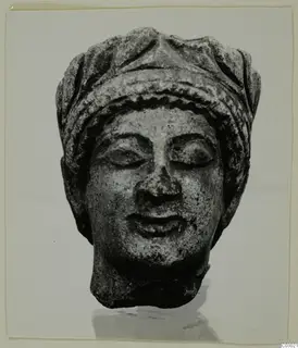 Limestone head from Vouni with downcast eyes and a banded headdress, shown from the front.