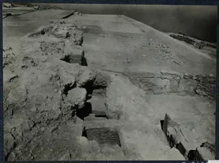 Excavated stone walls and a stepped recess at Vouni palace, with a flat cleared surface beyond