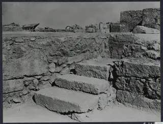 Stone steps leading up between ancient masonry walls at the palace at Vouni, with ruined walls behind.