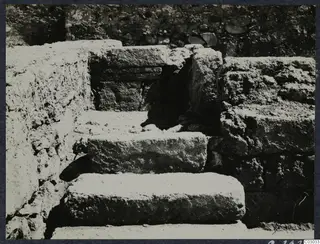 Stone steps leading up to a dark opening, with rough stone walls on either side, at the palace at Vouni