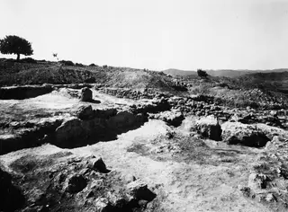 Excavated ruins of the Heracles chapel at Vouni, with low walls and bare stone foundations under a sparse hillside.