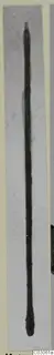 Long thin bronze toilet implement with a pointed top, photographed upright against a grey background