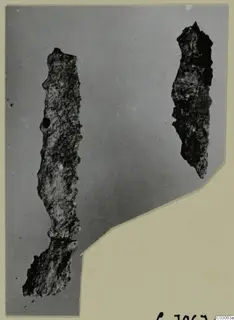 Two corroded iron tools lying upright on a grey backdrop