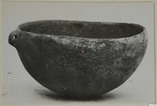 Pottery Black Slip Ware bowl with a small pierced lug handle, shown against a plain light background.