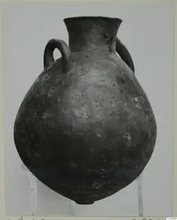Black Slip Ware hydria with a round body, narrow flaring neck and two loop handles, photographed on a stand