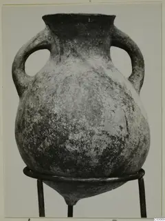 Black Slip Ware amphora with two handles, photographed on a three-legged metal stand
