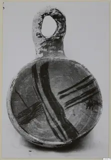 Round pottery vessel with a loop handle and broad dark painted bands, photographed against a plain background