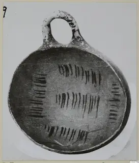 Pottery bowl with a loop handle, its interior decorated with dark vertical strokes in bands