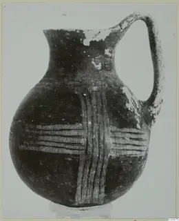 Jug with a single loop handle and bands of pale painted lines in cross-like pattern on a dark body