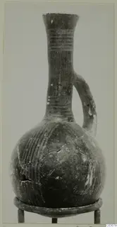 Single-handled jug with a flaring rim, long neck and rounded body, with painted bands on the neck and stripes on the body.