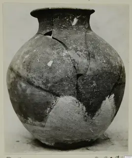 Jar in Plain White Hand-made Ware with a round body and flared rim, cracked and partly restored with light plaster patches
