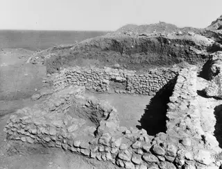 Excavated stone wall foundations of a house at Mersinaki, with the sea visible beyond the site