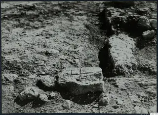 Squared stone block and low stone wall among loose stones in an excavated area at Vouni Palace