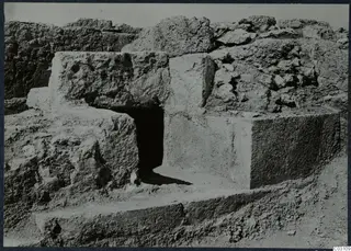 Large cut stone blocks and walls at the Vouni palace, with a dark doorway opening between them