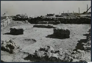 Excavated low stone walls and rectangular stone blocks at Vouni palace, with a wire fence behind
