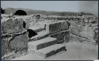 Stone steps of large blocks at the palace at Vouni, with ruined walls, a tree and hills behind
