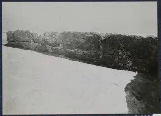 Long stone wall with a bright, bare ground surface in front, at the palace at Vouni.