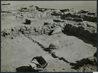 Excavated room at Vouni with two tapering vessels and a broken bowl lying in situ among stone walls