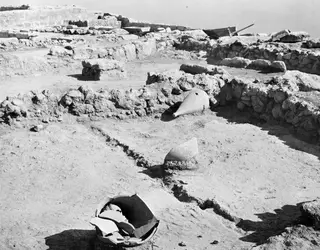 Room 107 at Vouni with finds in situ: two pointed vessels and a broken bowl among low stone walls
