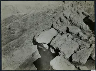 Large cut stone blocks and a dark pit during excavation at the palace at Vouni.