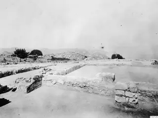 Excavated stone wall foundations at Vouni palace, with trees and hills in the background