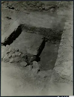 Excavation at the Vouni palace showing a square cut in the soil, with rough stone walls and loose rubble around it