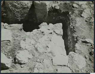 Excavation trench at Vouni with large stone blocks and loose stones lying in excavated soil.
