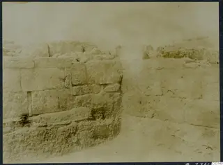Excavated stone walls of ashlar blocks at the palace at Vouni, with rubble on top and a hazy sky behind.