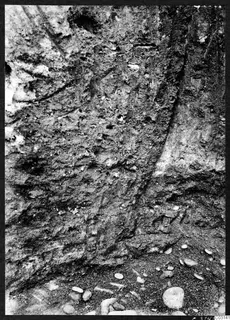 Soil section in pit J 20 at Mersinaki, showing layered earth with small stones and pebbles at the base