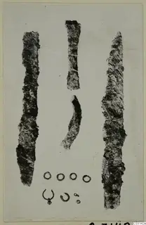 Corroded metal tools and small rings from Marion, laid out on a pale card.