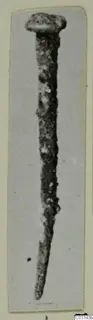 Corroded metal nail from Marion, head at the top, shown on a mounted photograph.