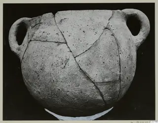 Plain White Hand-made Ware vessel with two loop handles, its broken pieces rejoined with visible cracks