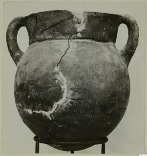 Two-handled globular pottery pot with a wide neck and cracks, shown on a three-legged metal stand