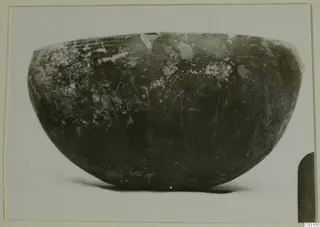 Dark rounded bowl with a wide mouth, photographed in profile on a pale background