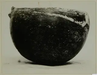 Rounded bowl with a small lug on the rim, photographed from the side, from the Lapithos Vrysi tou Barba tombs