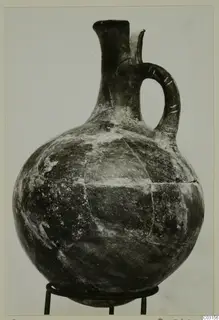 Pottery Red Polished I jug from Lapithos with a strap handle, shown on a three-legged metal stand