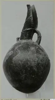 Pottery Red Polished III jug from Lapithos, with a tall flaring spout, loop handle and raised wavy decoration on the body