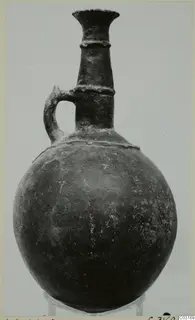 Pottery Red Polished II jug with a flared neck, raised bands and a single loop handle, shown on a stand