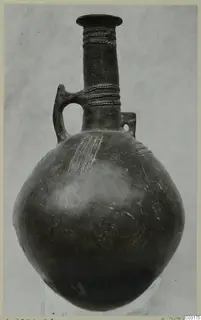 Pottery Red Polished III jug from Lapithos with a long neck, loop handle and impressed dotted bands on neck and body.