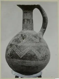 Pottery Red Polished II jug with pale zigzag and horizontal bands, shown on a ring stand against a plain background